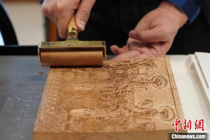 圖為徐晉林工作室工作人員正在給雕好壁畫的版面滾油墨?！【琶赖┰?　攝