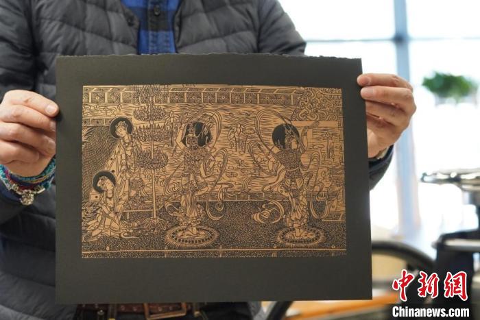 圖為手工書藝人展示敦煌雕版壁畫印刷品。　九美旦增 　攝