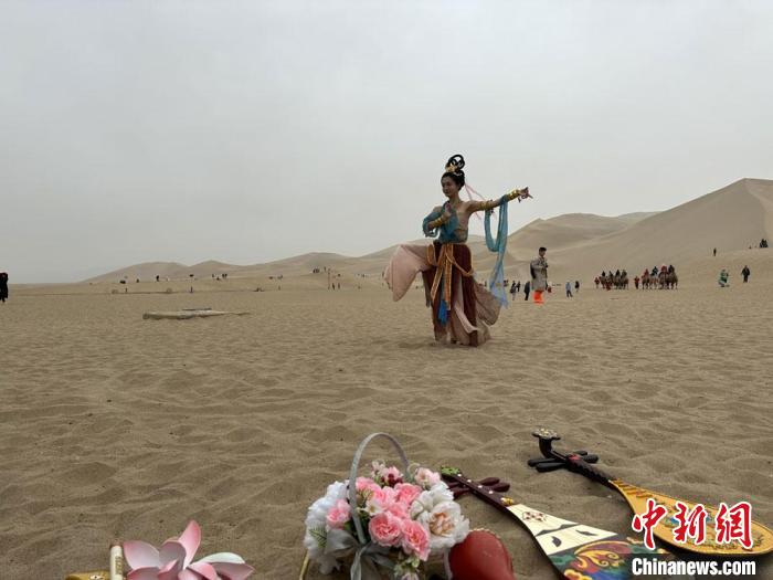 圖為2023年4月底，敦煌大漠“逐舞者”奧楠在鳴沙山月牙泉景區(qū)視頻直播敦煌舞?！●T志軍 攝