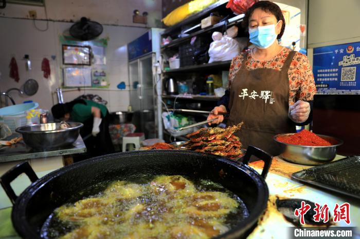 圖為平安驛·河湟民俗文化體驗(yàn)地內(nèi)的商戶炸干板魚?！⊙Φ?攝