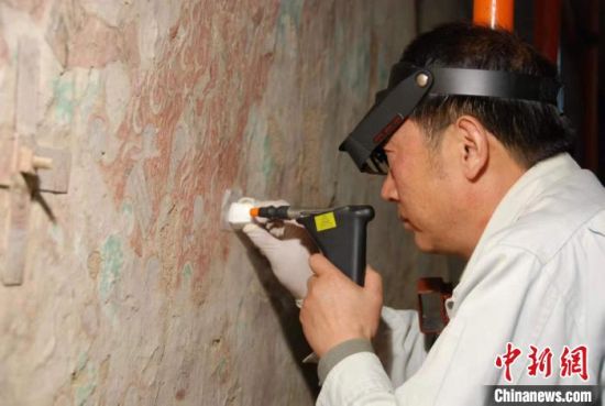 敦煌研究院研究員樊再軒進行壁畫修復(fù)。(資料圖)張云文 攝