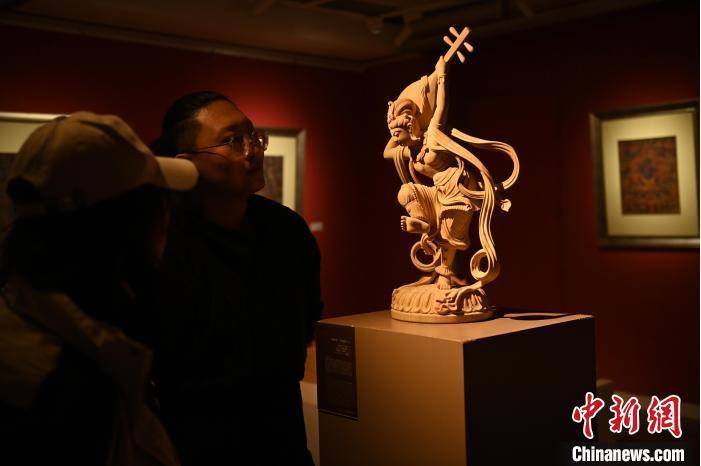 圖為季茂杰向參觀者介紹自己創(chuàng)作敦煌木雕的過程。李亞龍 攝</p>
<p>